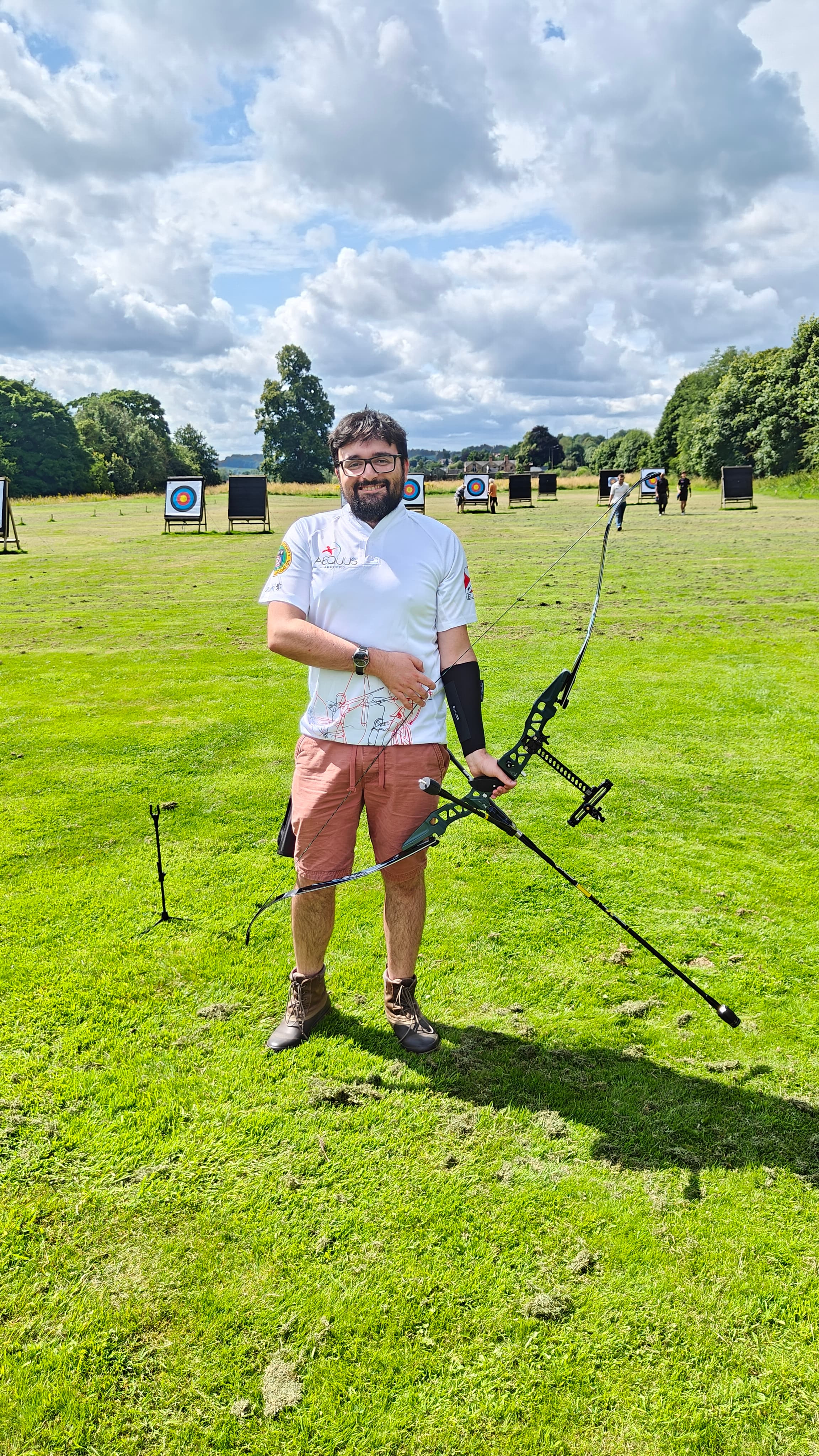 Francesco at the archery range with a recurve bow, targets visible in the background